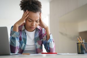 Tired african american teen girl suffer headache doing homework at laptop. Difficult elearning